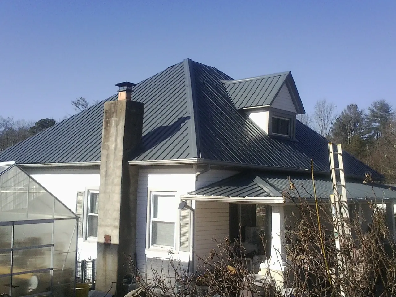 Dark blue standing seam metal roof on a white farmhouse with dormer — Slate & Tile Roof Repair by Roofing Brothers in Zarephath
