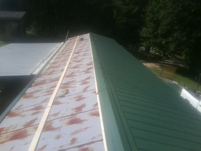 Old rusted panels beside newly installed green metal roofing — Wind Damage Roof Repair by Roofing Brothers in Zarephath