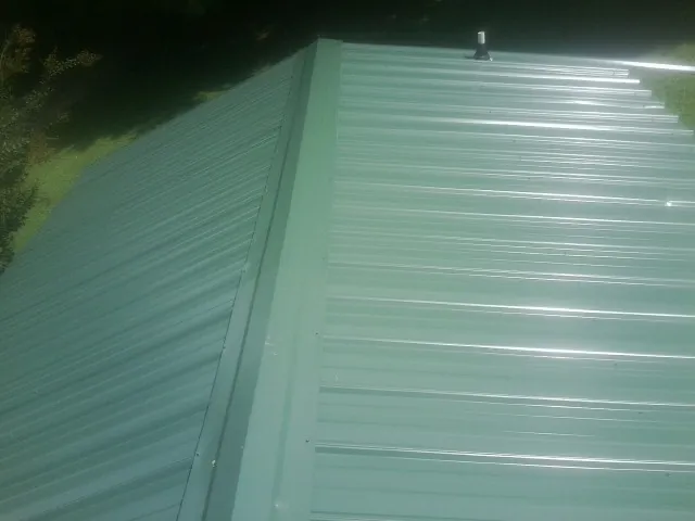 New green metal panels meeting at the ridge of a roof — Flat Roof Repair work by our crew in Zarephath