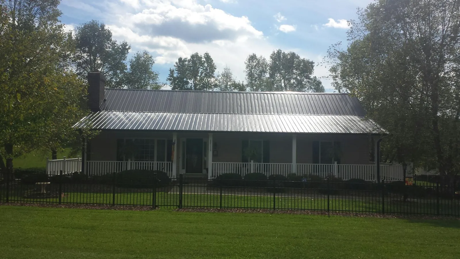 Gray metal roof on a brick ranch with a full width front porch — Gutter Guard Installation work by our crew in Zarephath