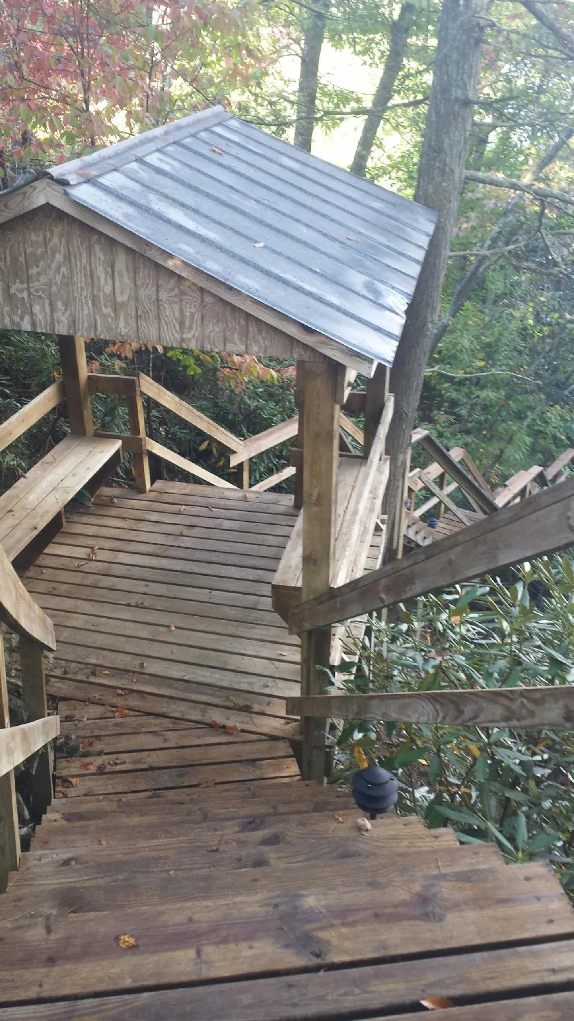 Metal roofed shelter over wooden steps on a wooded walkway — Skylight Repair & Installation work by our crew in Zarephath