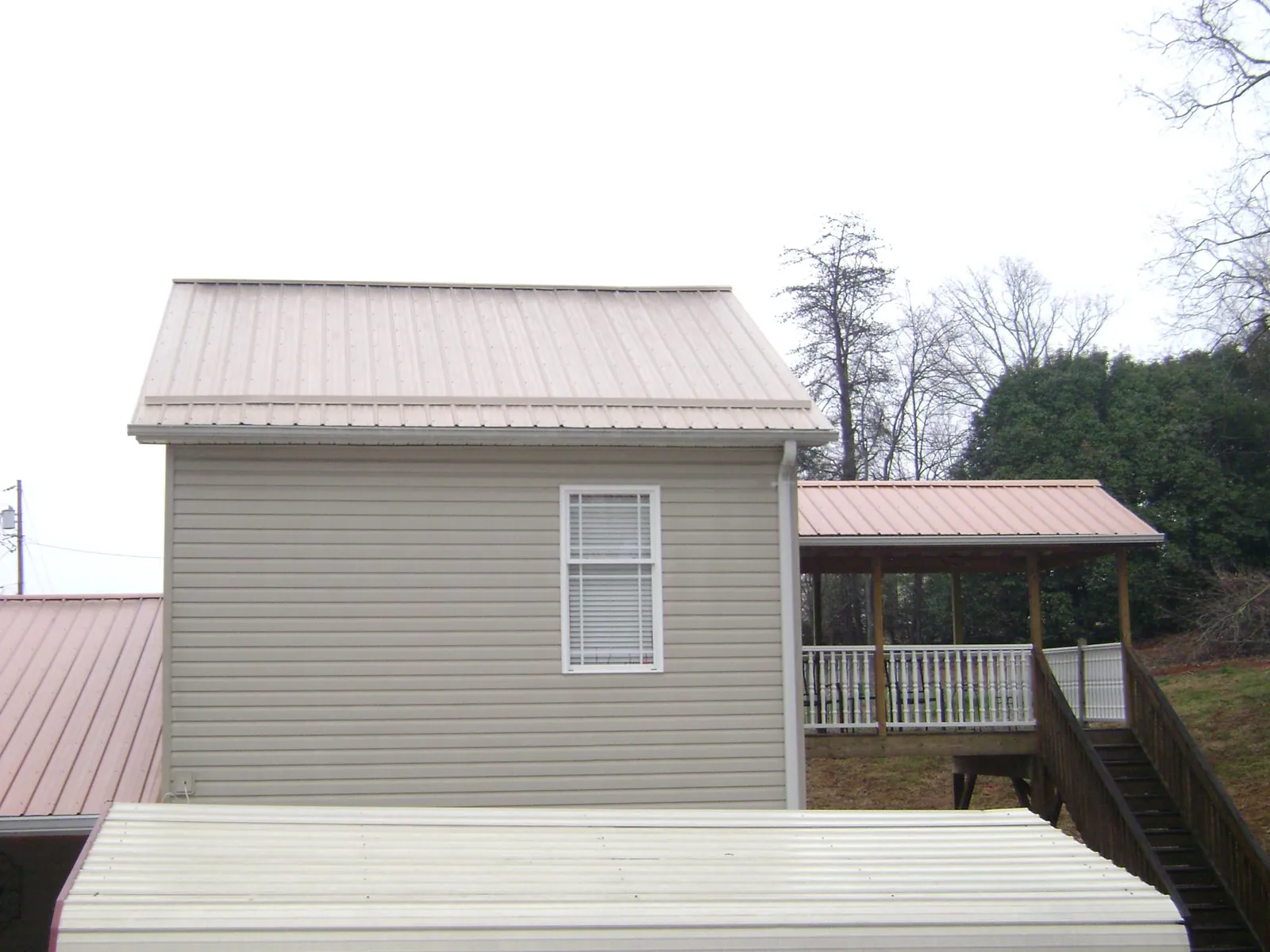 Tan metal roofs on a two story addition and attached porch, from a Roof Replacement job in Zarephath