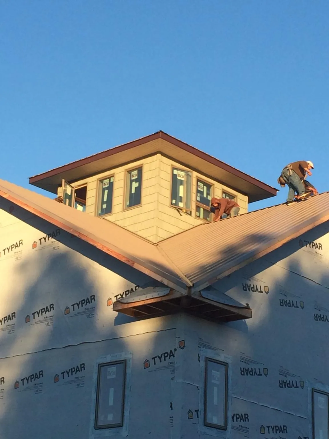 Roofers working around a rooftop cupola on a new metal roof at sunset — Roof Waterproofing in Zarephath by Roofing Brothers